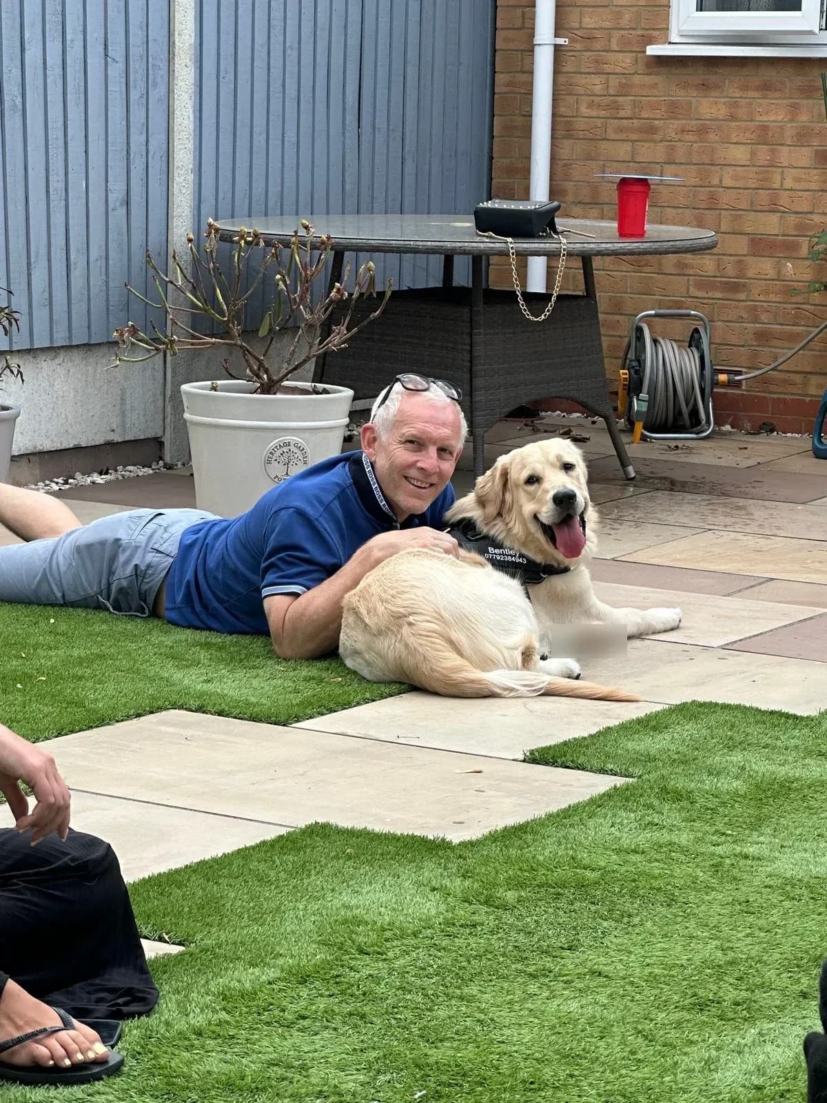 Bentley, a golden retriever puppy, lying on the grass next to Lee’s dad